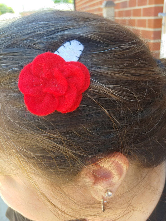red flower hairclip with white base and black blanket stitching on someone's head
