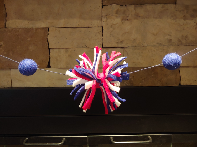 Handmade patriotic felt garland with red, white, and blue pom-poms.