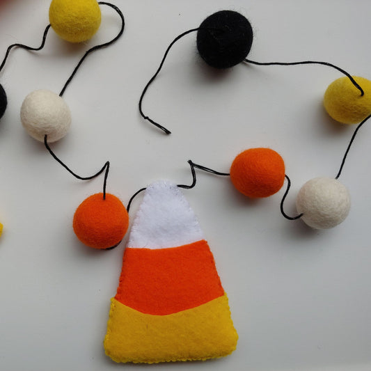 Handcrafted Candy Corn Felt Garland featuring yellow, orange, white, and black felt candy corn pieces with felt balls. A festive Halloween and fall decoration.