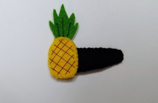 Handmade felt Pineapple Hair Clip with bright yellow and green felt, brown stitched details, and a secure snap clip. A playful, tropical accessory.
