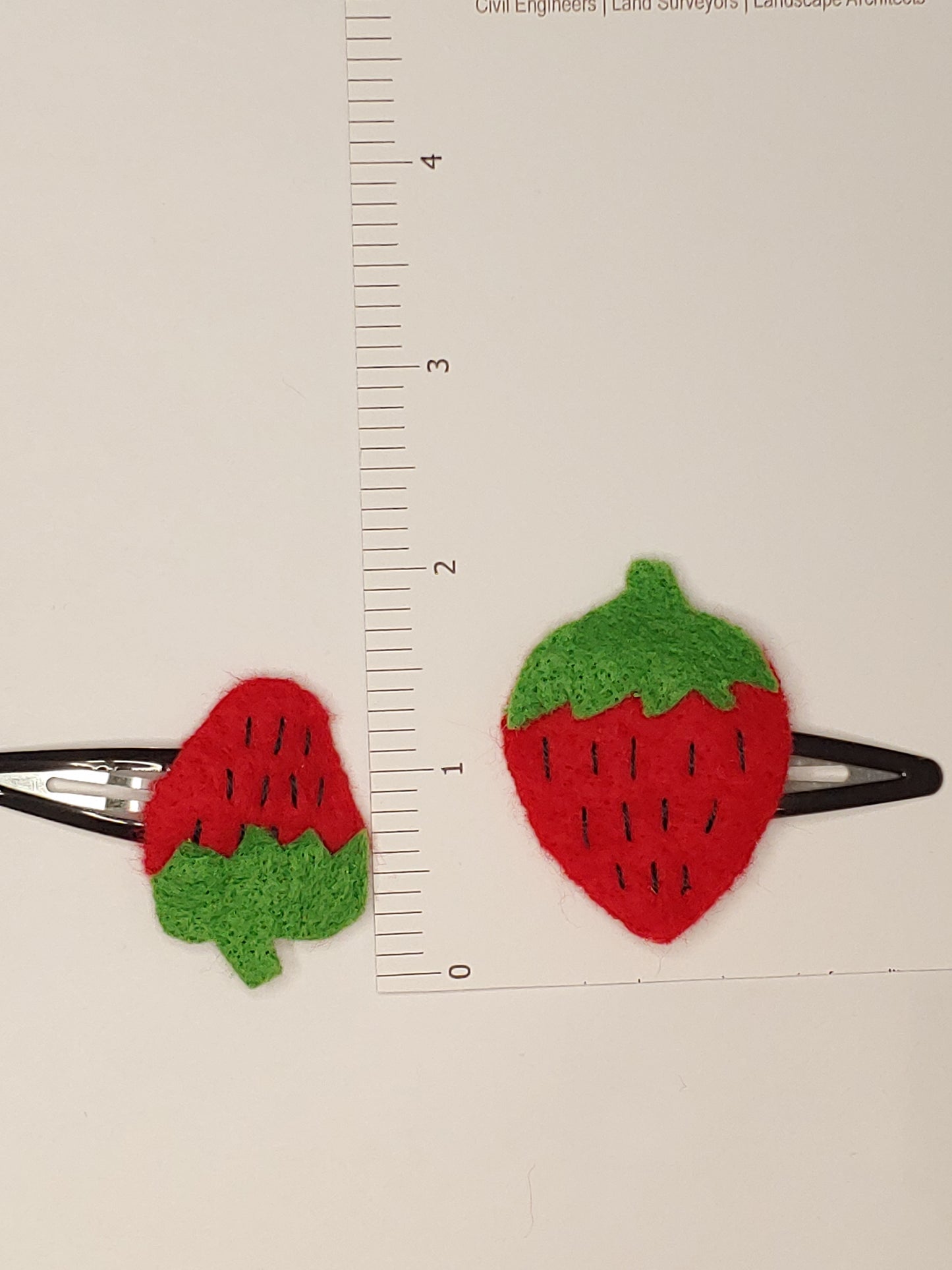 Handmade Mommy & Me Strawberry Hair Clip Set featuring vibrant felt strawberries on black snap clips next to ruler. A charming, matching accessory for moms and daughters.