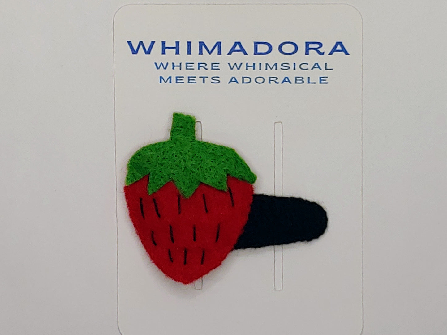 Handmade felt Strawberry Delight Hair Clip with vibrant red and green felt, black stitched details, and a secure snap clip. A playful, fruity accessory.