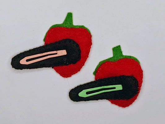 Handmade felt Strawberry Delight Hair Clip with vibrant red and green felt, black stitched details, and a secure snap clip, back side image. A playful, fruity accessory.