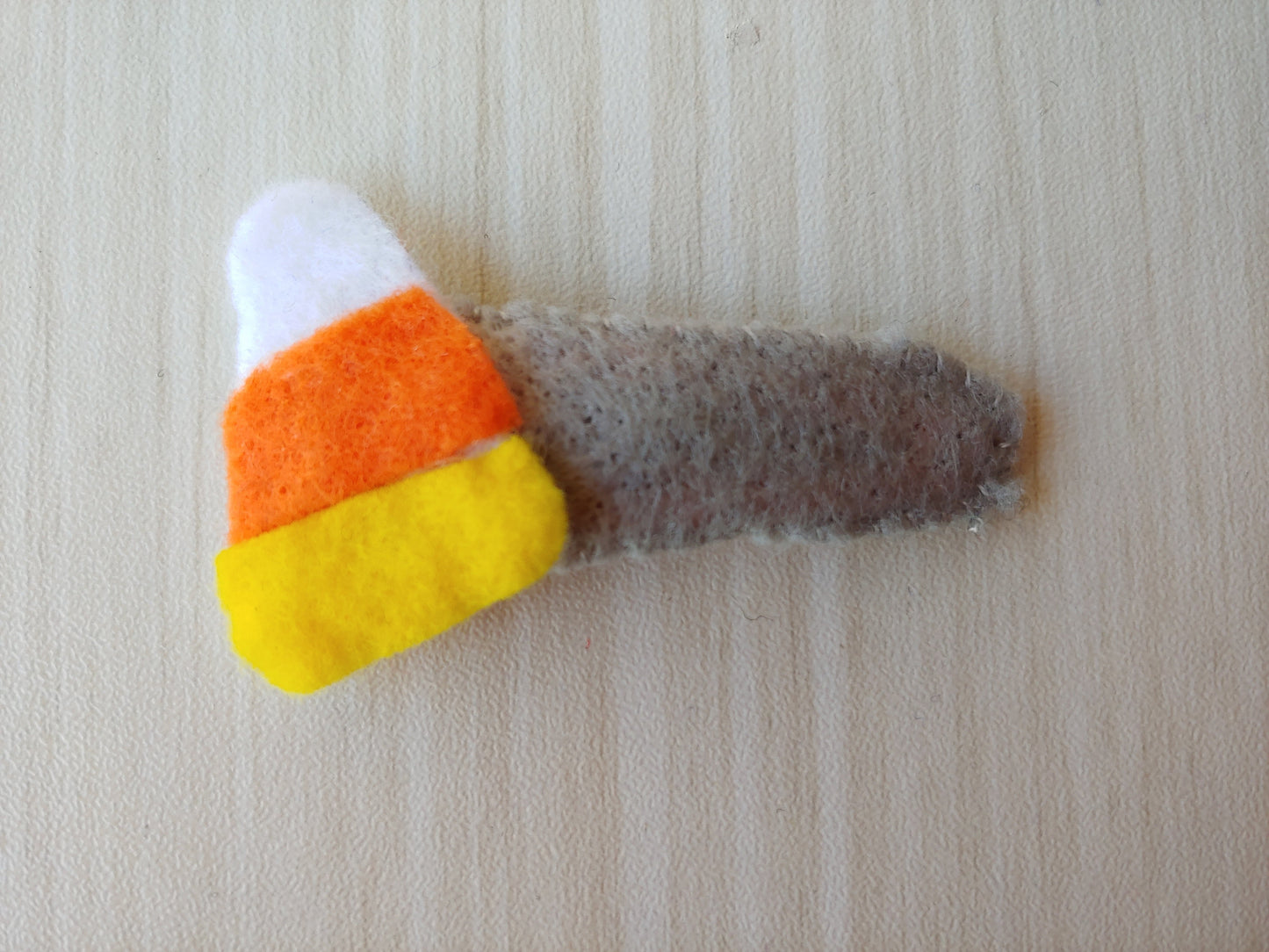 Handcrafted Candy Corn Felt Hair Clip featuring gray, white, yellow, and orange felt on a secure snap clip. A festive fall hair accessory.