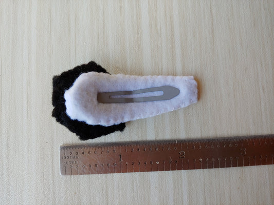 Black felt cut to hexagon shape with white lines stitched on to create spiderweb effect. Attached to snap clip covered in white felt. About 24 tenths long.