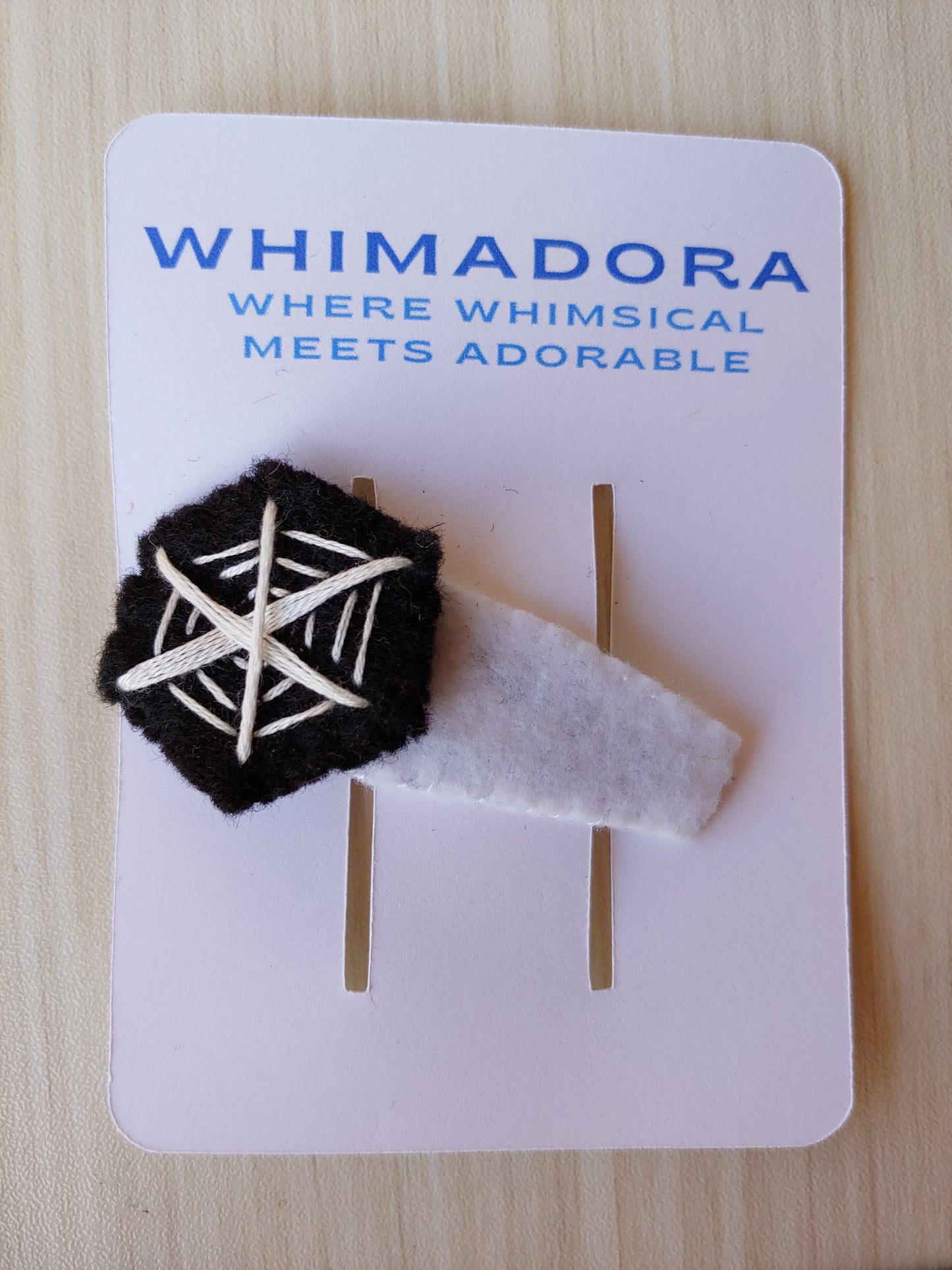 Handcrafted Spiderweb Felt Hair Clip featuring black felt with white embroidery on a secure snap clip. A spooky and stylish Halloween accessory.