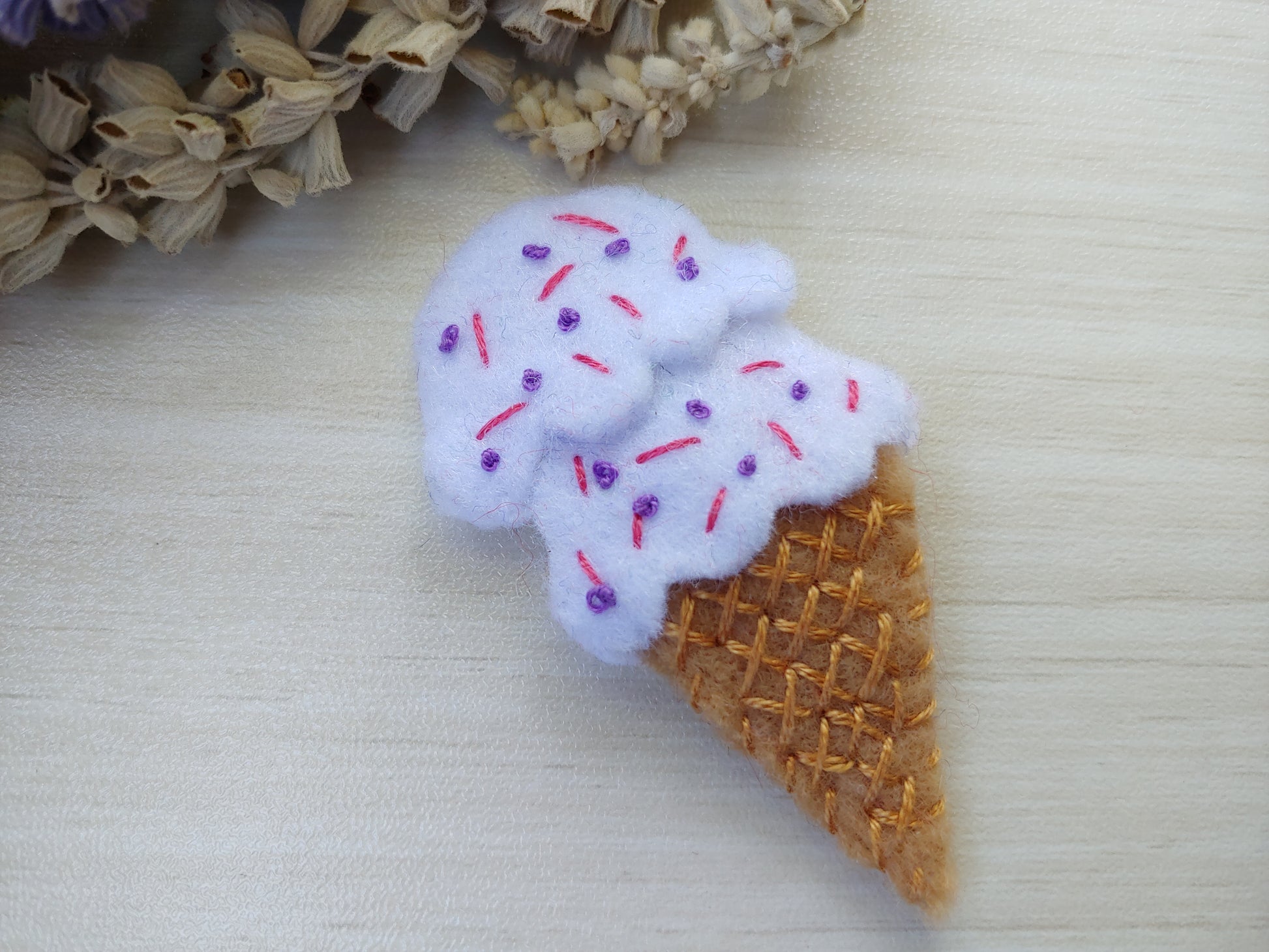 Handcrafted White Ice Cream Cone Felt Hair Clip featuring a tan cone, white scoops, and colorful sprinkles on a secure snap clip. A fun, sweet accessory.