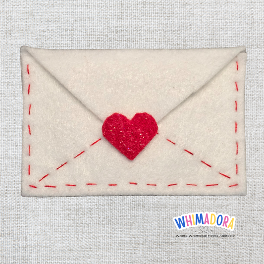 Envelope-shaped pouch with a red heart on a textured gray background, branded 'WHIMADORA'.
