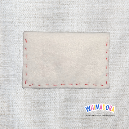Rectangular white felt patch with red stitching on a textured gray background, featuring the Whimadora brand.