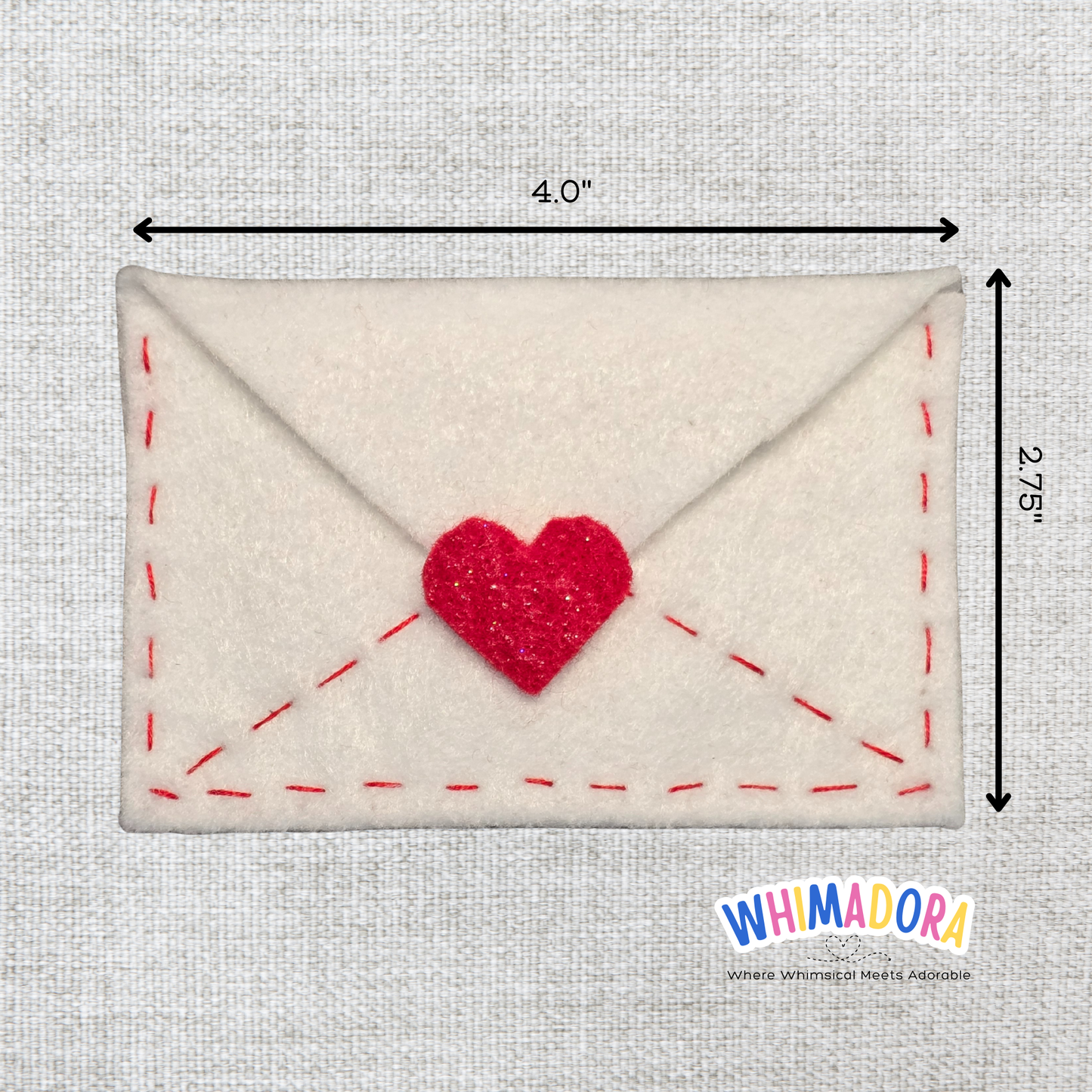 Felt envelope with a red heart and measurements on a gray background, Whimadora brand visible.