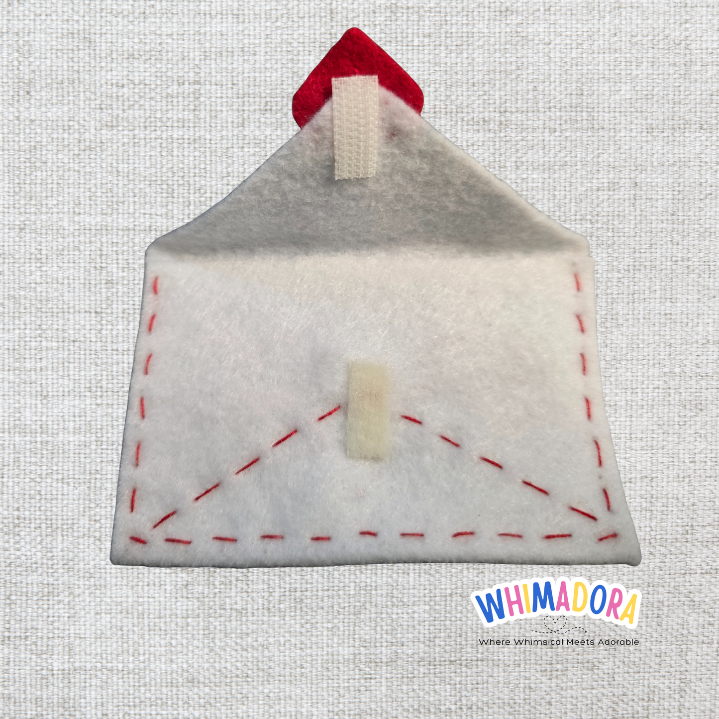 Felt house-shaped pouch with red roof on a textured gray background, branded 'WHIMADORA'.