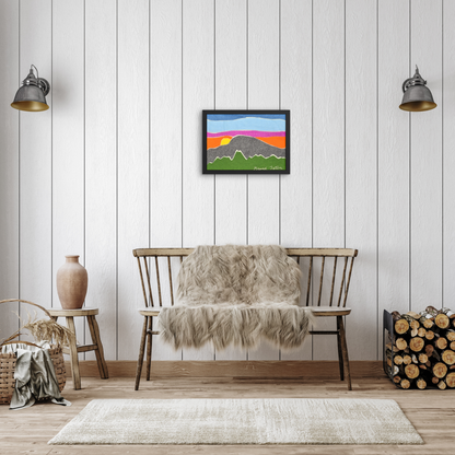 Framed Grand Teton felt wall art displayed in a cozy, modern rustic living space. The artwork hangs on a white wood-paneled wall above a bench with a faux fur throw. The room includes minimal décor like a ceramic vase, a wicker basket, and a firewood stack, highlighting a warm and inviting atmosphere.