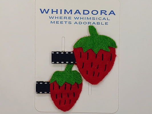 A set of strawberry hair clips on an alligator clip that was wrapped with a ribbon.