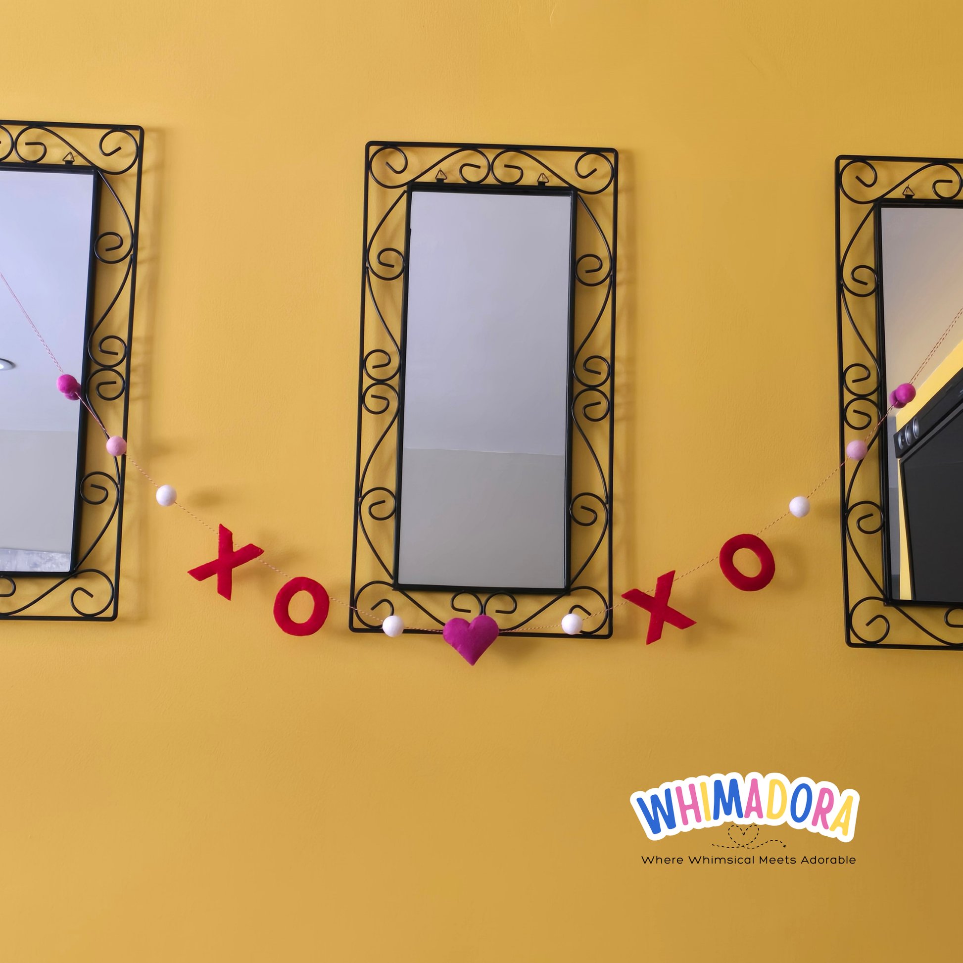 Three decorative mirrors with ornate frames on a yellow wall, featuring 'xo' and a heart symbol.