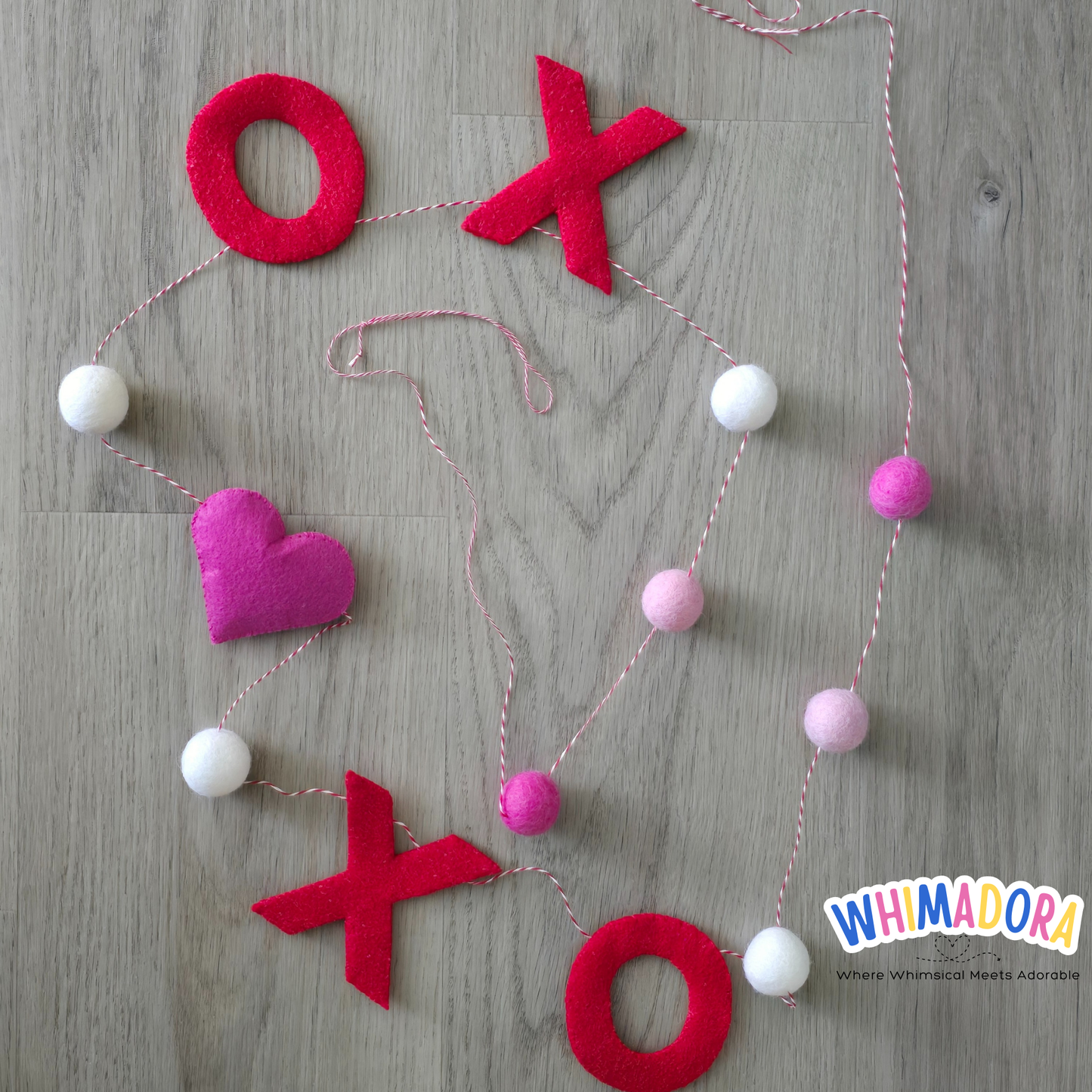Decorative string with red letters 'O' and 'X', pink heart, and colorful beads on a wooden surface.