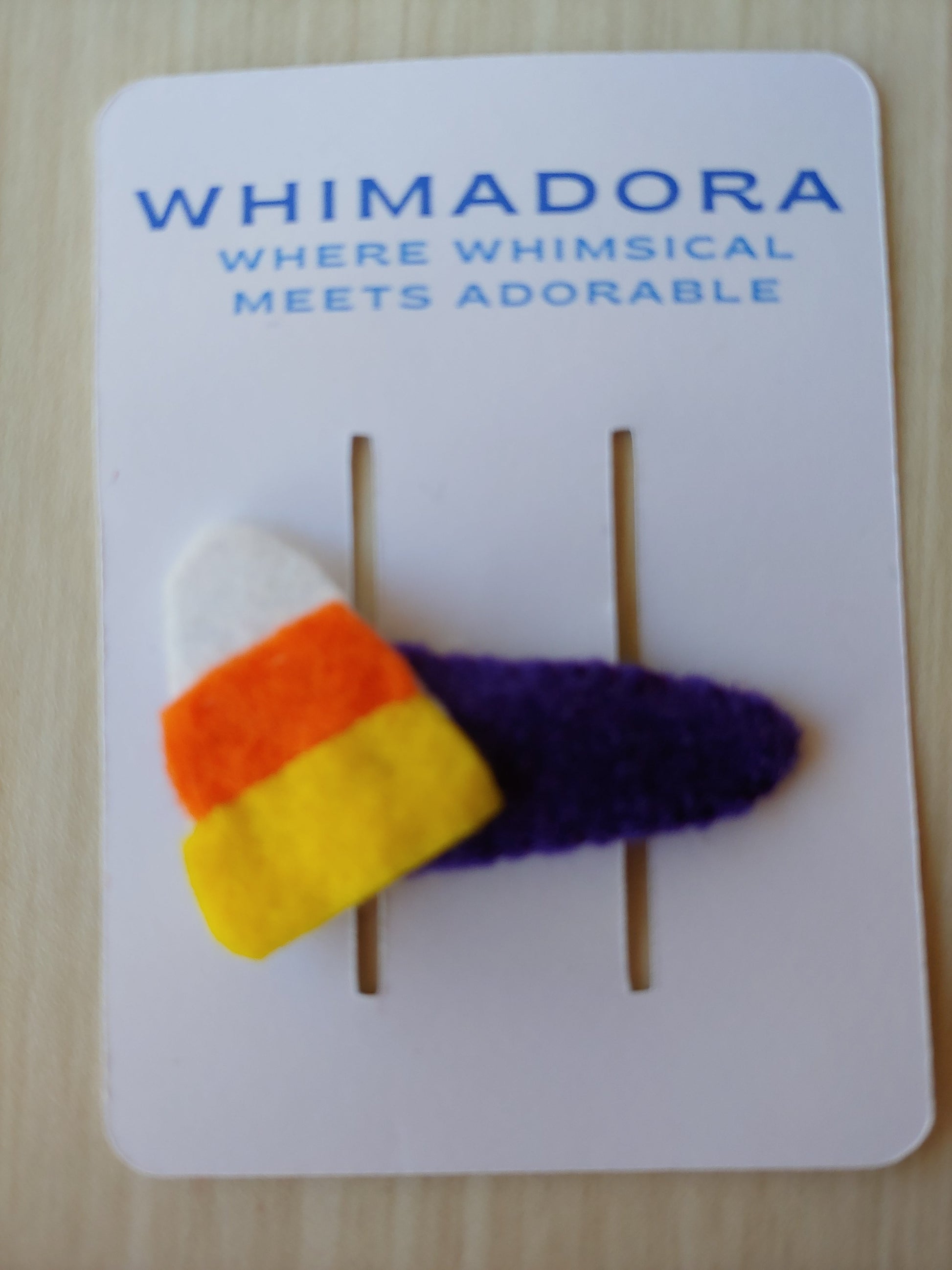 Candy Corn shaped cutout attached to snap clip covered in purple felt shown on packaging card.