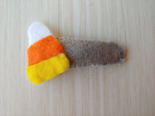 Candy Corn felt cutout attached to snap clip covered in gray felt.